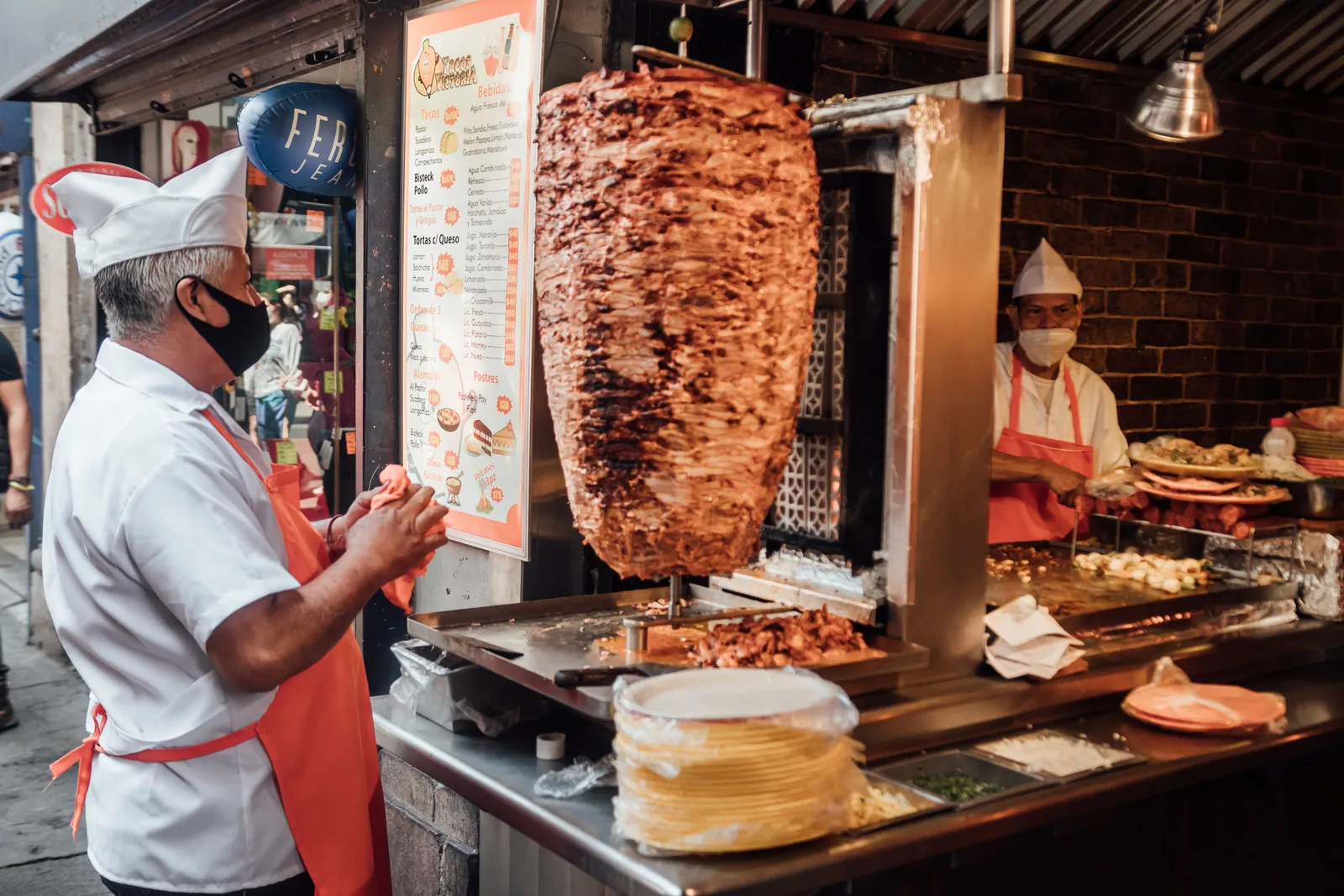 A taquero carving pork from a vertical spit