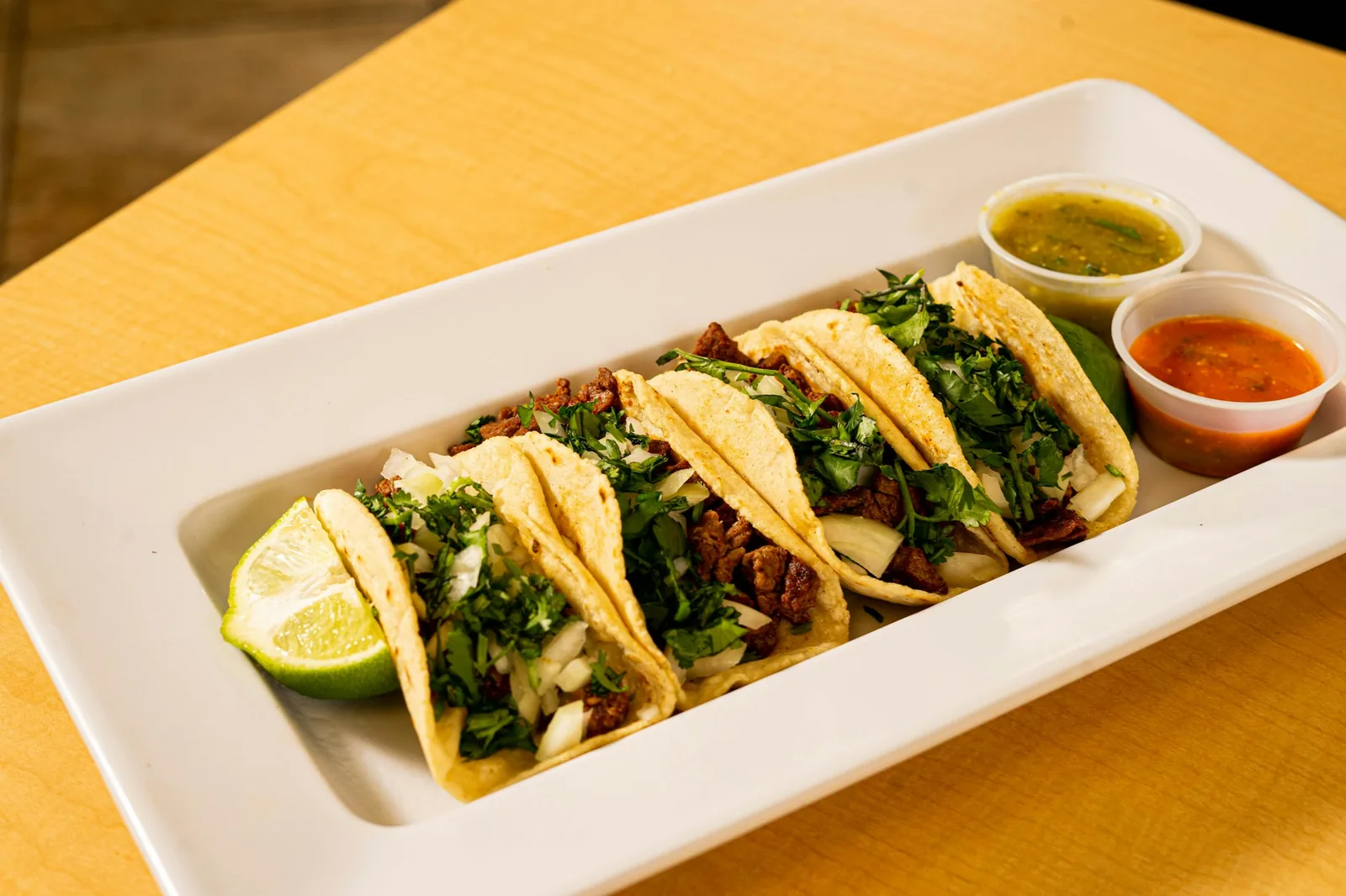 Al pastor-style tacos topped with onion, cilantro and lime