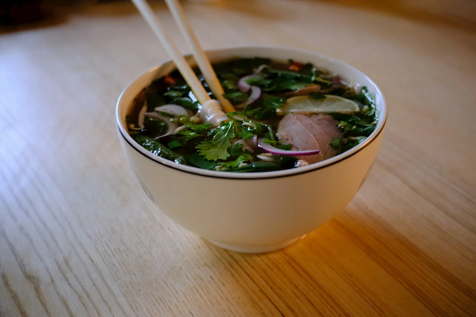 A cup of consomé topped with onion and cilantro