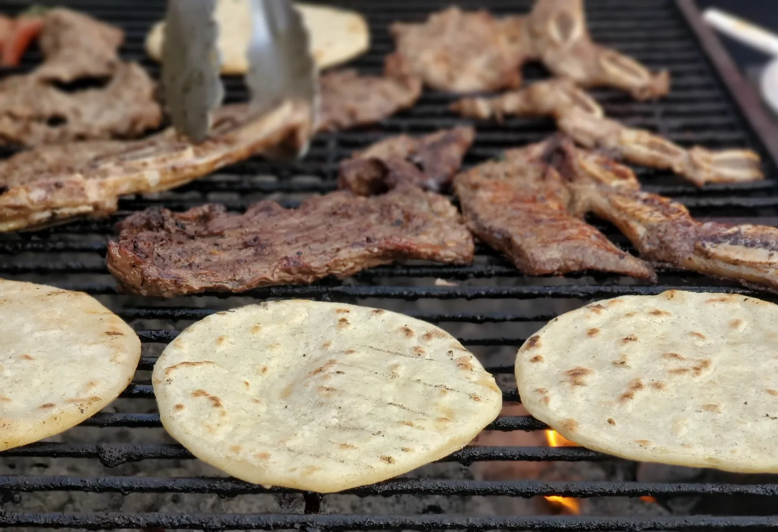 Beef grilling over charcoal, the method used for carne asada