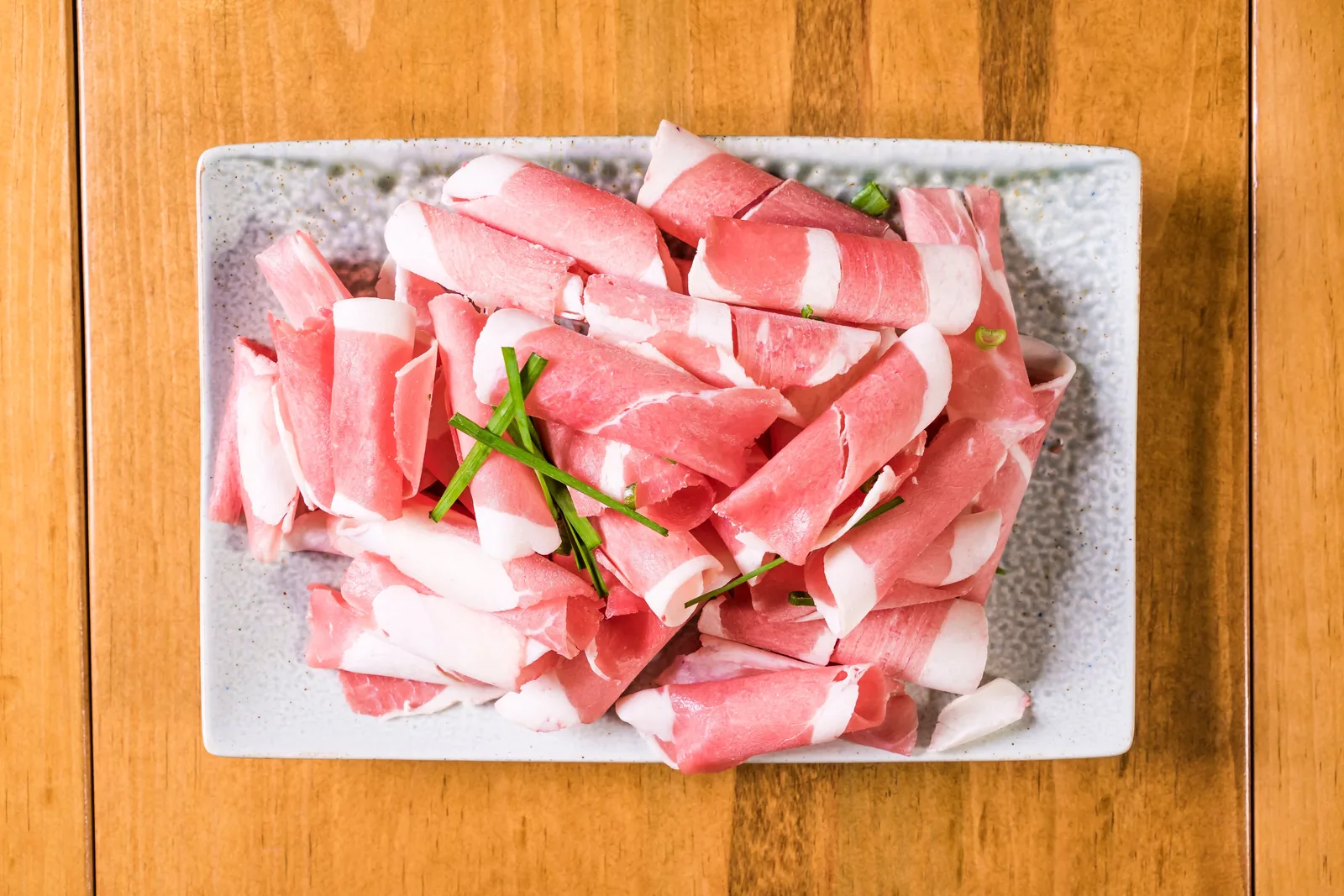 Thinly cut beef cooking on a flat-top griddle