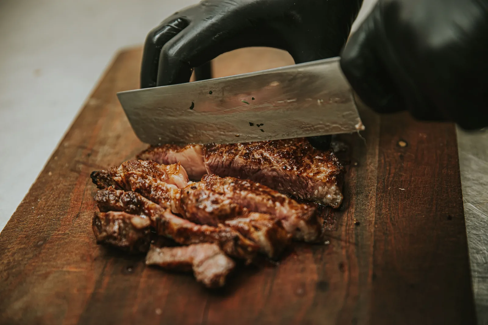 Cooked steak being sliced thinly across the grain