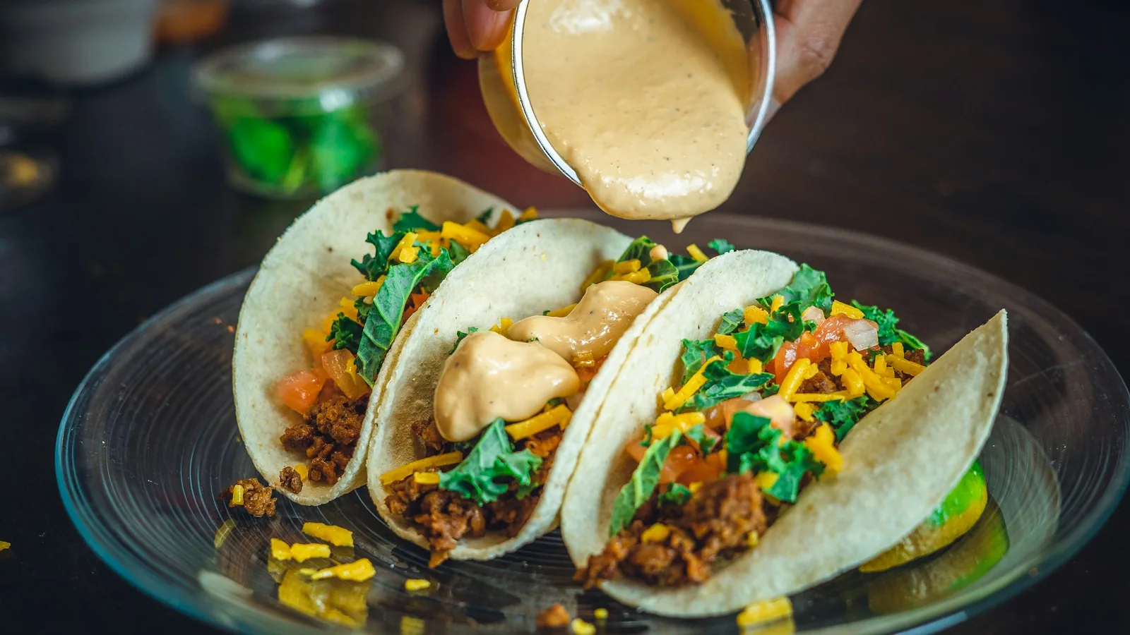 Cream drizzled in stripes over a plate of tacos