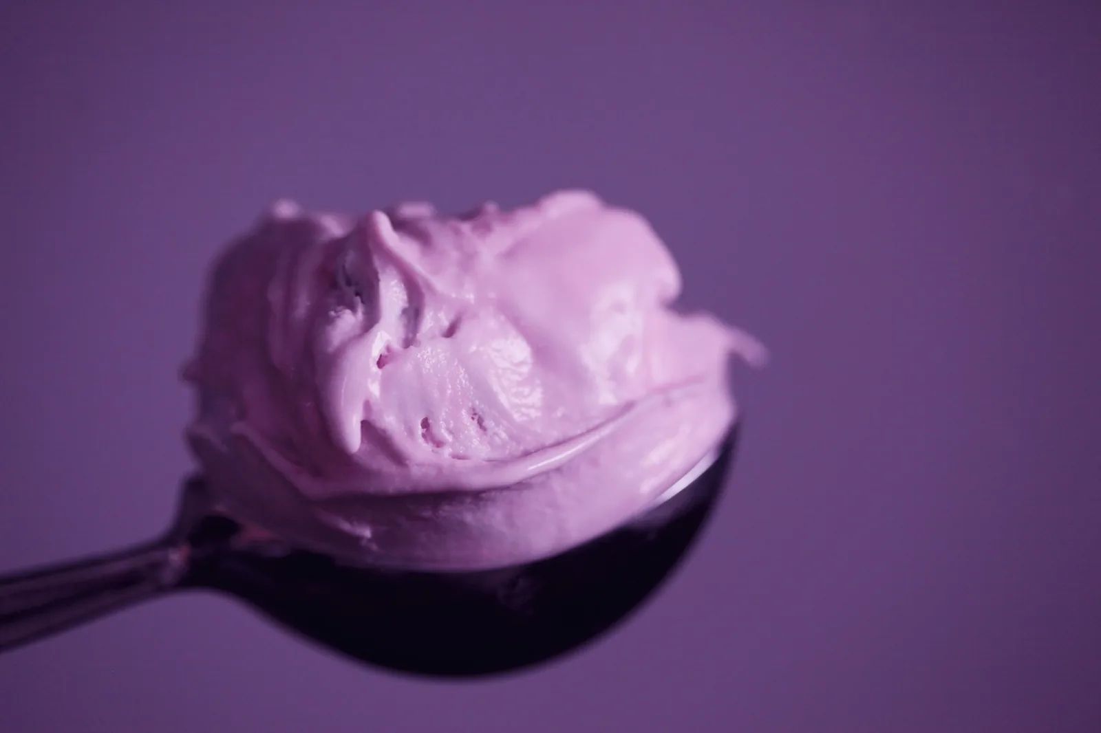 Thick sour cream held in a spoon above a bowl