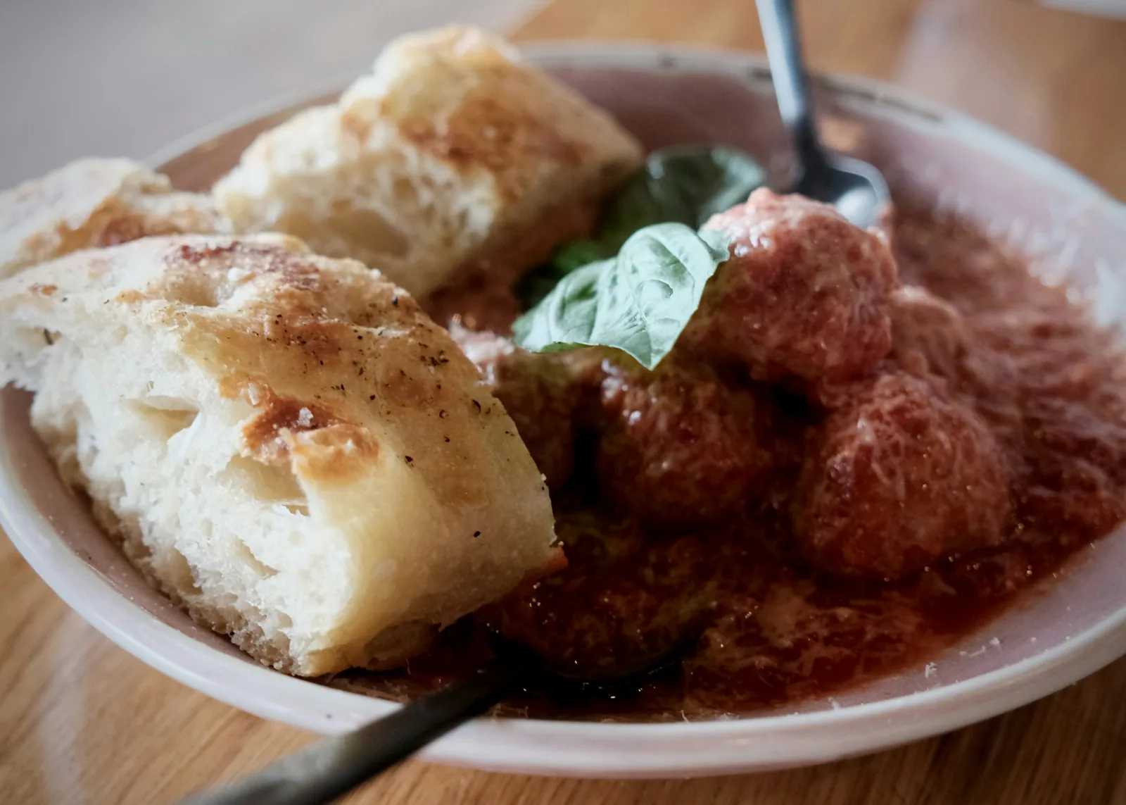 A bread roll submerged in thin red sauce