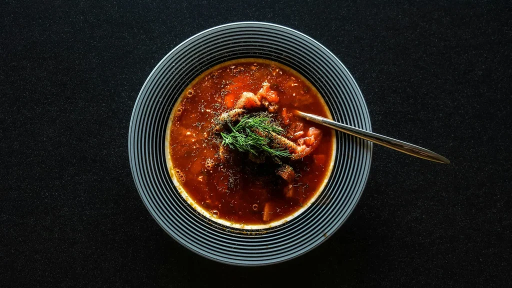 A bowl of red chilli broth with hominy