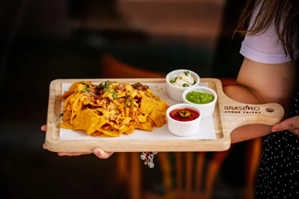 A platter of tortilla chips under melted cheese and jalapeños