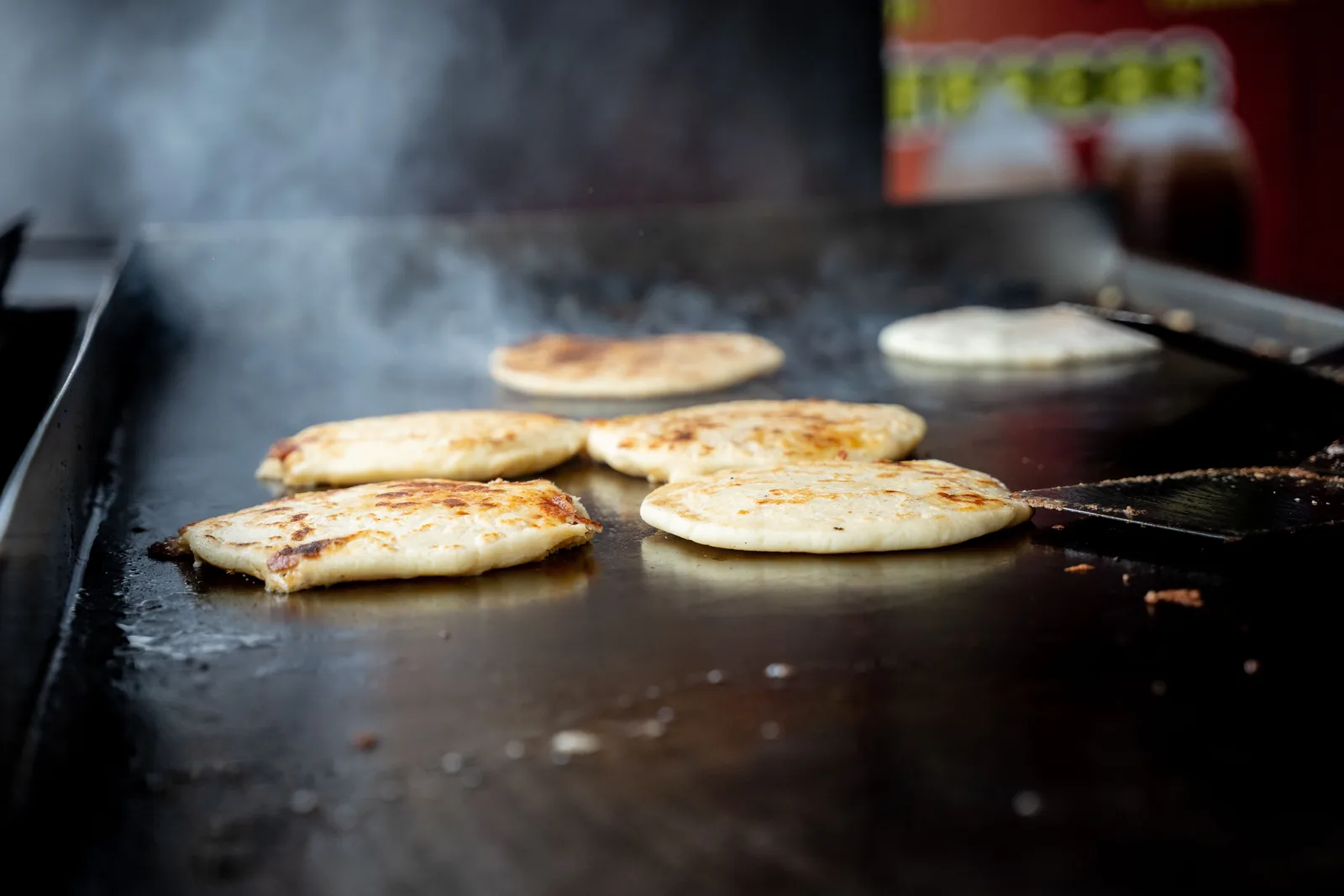 Masa cakes cooking on a flat griddle