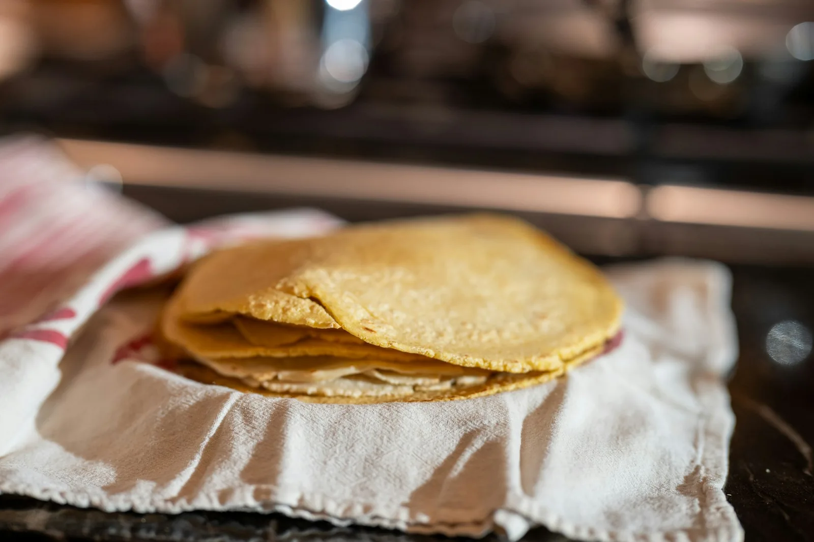 A stack of warm corn tortillas resting on a griddle