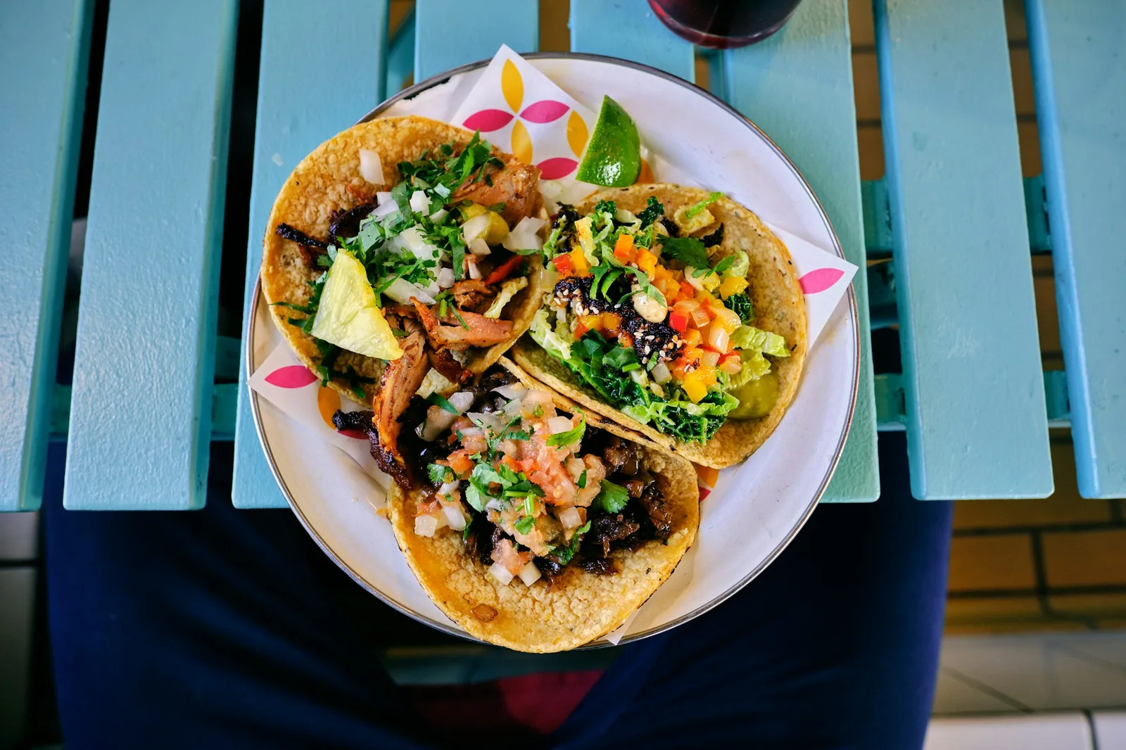 A small corn-tortilla street taco held in one hand